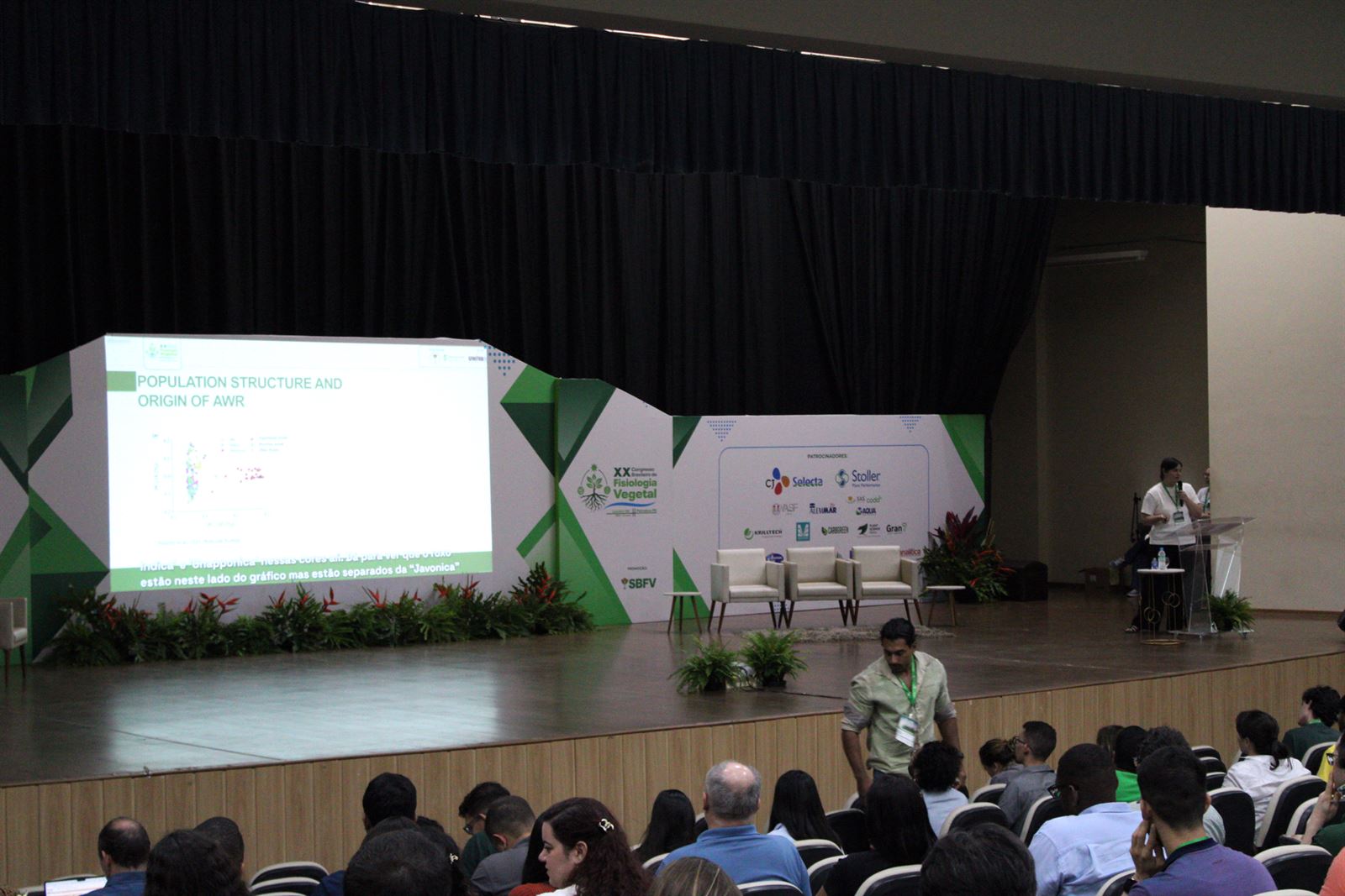 Auditório principal do congresso, lotado. No telão, um slide em inglês com a legenda em português no rodapé.